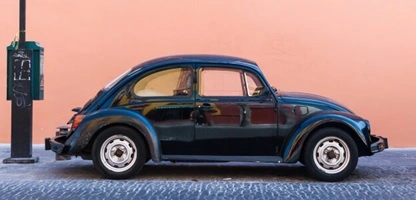 A classic dark green Volkswagen Beetle Car is parked