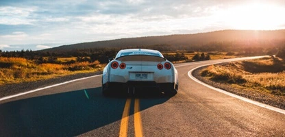 A white sports car drives on a winding road